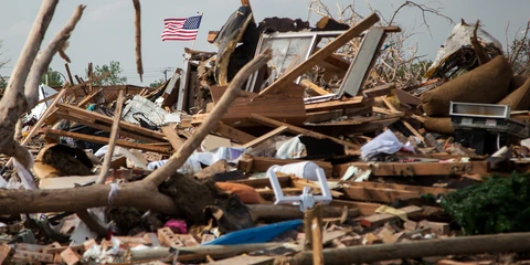 Tornado damage rubble, with an American flag flying above