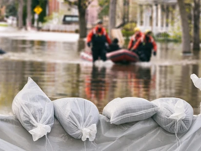 Flooded houses surrounded by sandbags with flood rescue raft transporting people