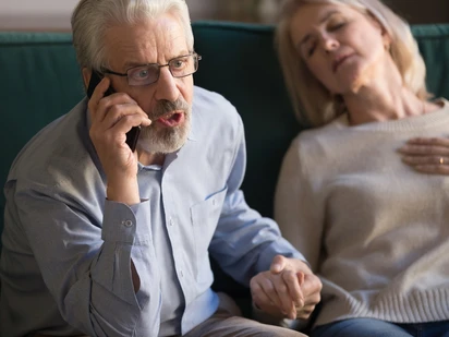 Man on the phone with a woman next to him who has fainted