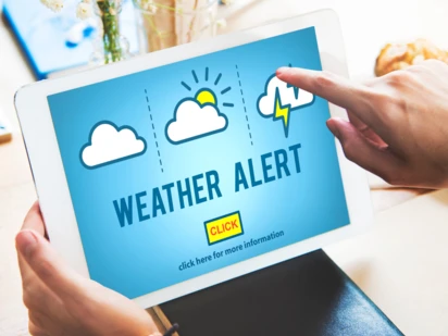 Person clicks on weather alert message on a tablet. 