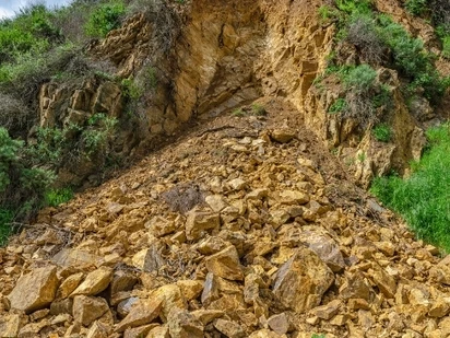 Dirt and rocks pile up at bottom of hill from landslide.