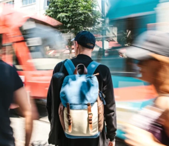 Man with backpack stands out in crowd of blurred street imagery.