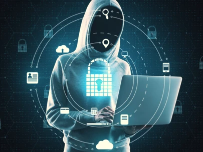 Hacker with no face in hoodie working on laptop