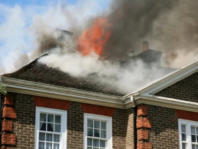 Brick house with roof on fire and smoke covering sky