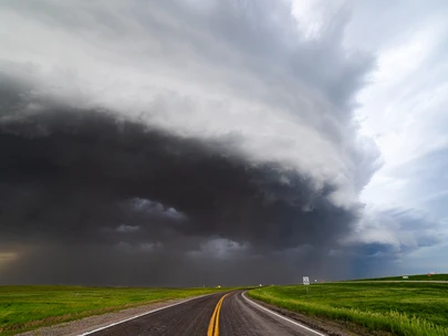 Dark derecho clouds swirl over highway.