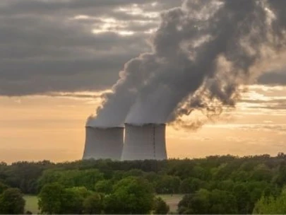 Nuclear power plant in the distance with smoke rising from the facility into the sky.