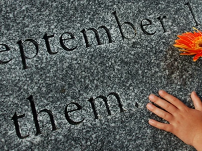 Child's hand places flower on September 11, 2001 Memorial.